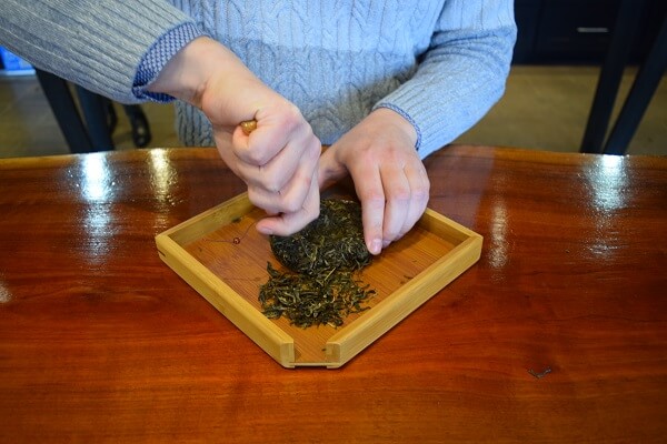 breaking off pieces of a puer before it is  brewed gongfu style
